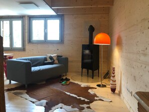Ein gemütliches Zimmer mit einer Couch, einem Kamin, einem Teppich und einer Lampe.