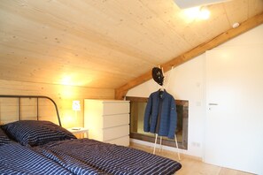 Ein Schlafzimmer mit einem Bett, einem Schminktisch, einem Fenster und einem Kleiderständer.