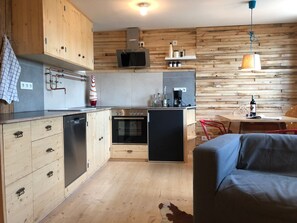 Eine moderne Küche mit Holzschränken, einem eingebauten Ofen und einer Kaffeemaschine.