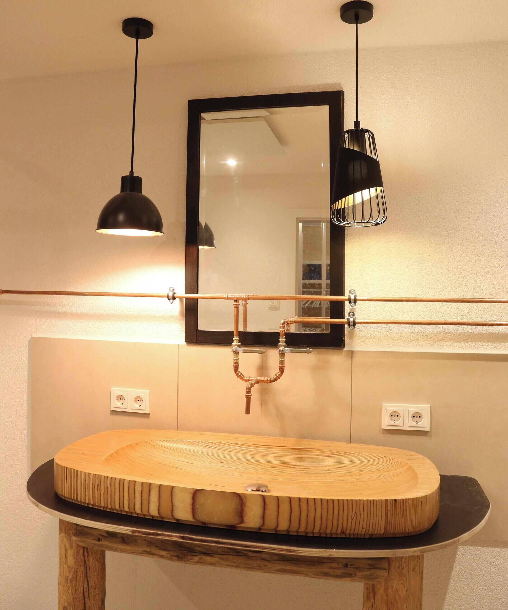 A bathroom with a wooden vanity, a mirror, and pendant lights.