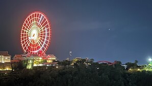 A large Ferris wheel at night with surrounding buildings and trees. - Cozy studio in Sapphire Ha Long with Sun Wheel view (Hồng Gai)