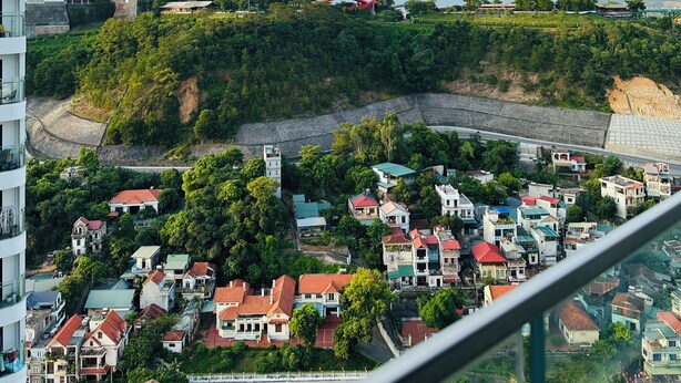 A residential area with houses, a red roller coaster, and a large Ferris wheel. - Cozy studio in Sapphire Ha Long with Sun Wheel view (Hồng Gai)