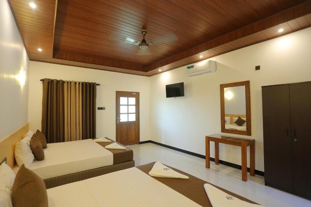 A hotel room with two beds, a ceiling fan, a TV, a mirror, and a wardrobe.
