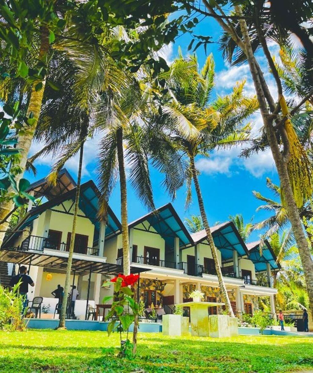 A resort with multiple-story buildings, a covered outdoor area, and lush tropical vegetation.