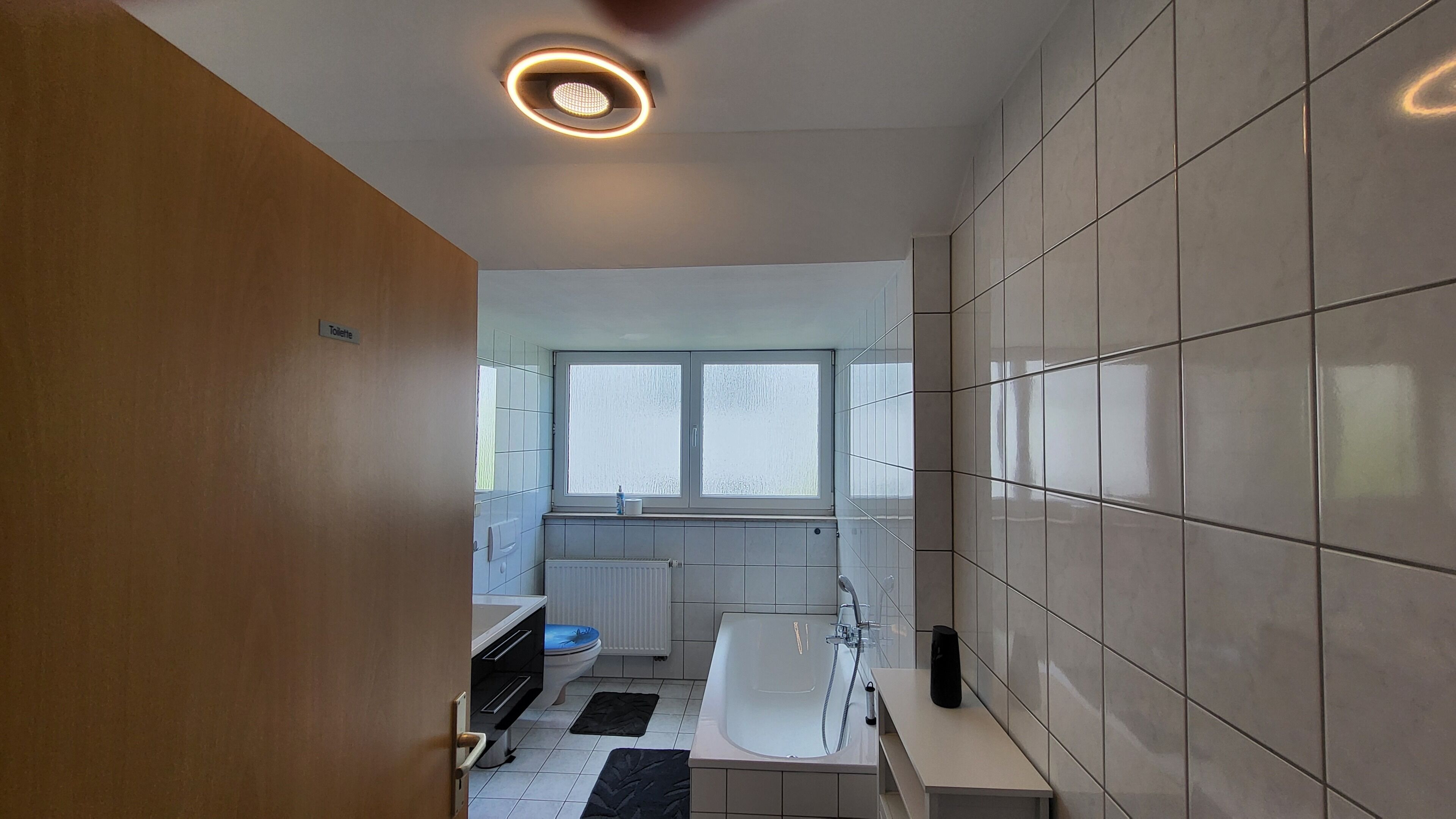 A modern bathroom with a bathtub, a toilet, and a window.