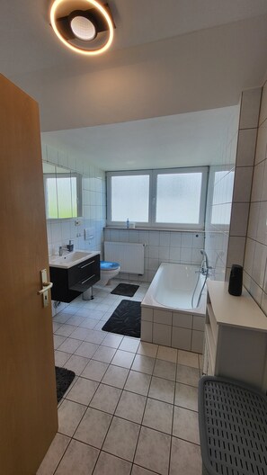 Et moderne badeværelse med badekar, toilet og håndvask.