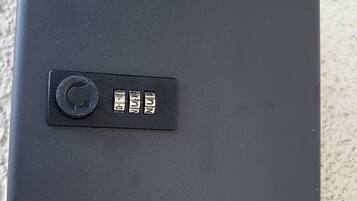Un objeto rectangular negro con un botón circular y tres etiquetas metálicas con números.