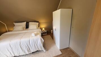 A bedroom with a bed, nightstand, lamp, and wardrobe.