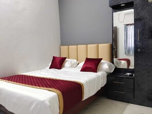 A bed with a headboard, a bedside table, and a mirror. - Shreesree Homestay (Tiruvannamalai)