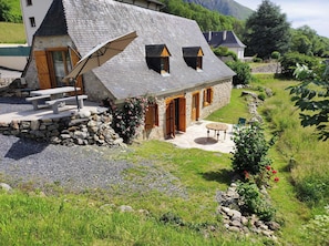 Une maison en pierre avec un toit en pente, un mur de pierre et un jardin fleuri.