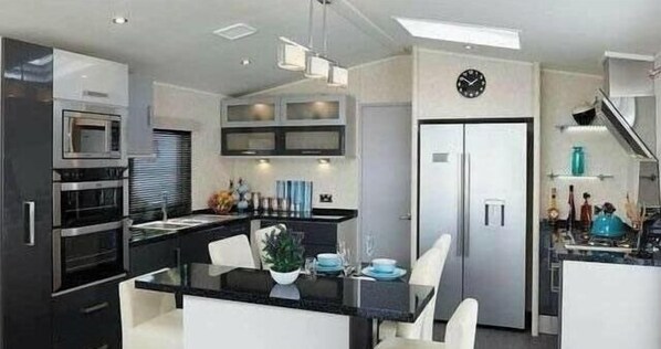 A modern kitchen with a central island, built-in appliances, and a dining area. - Ocean Edge Leisure Park - Holiday Accommodation 1317 (Morecambe)