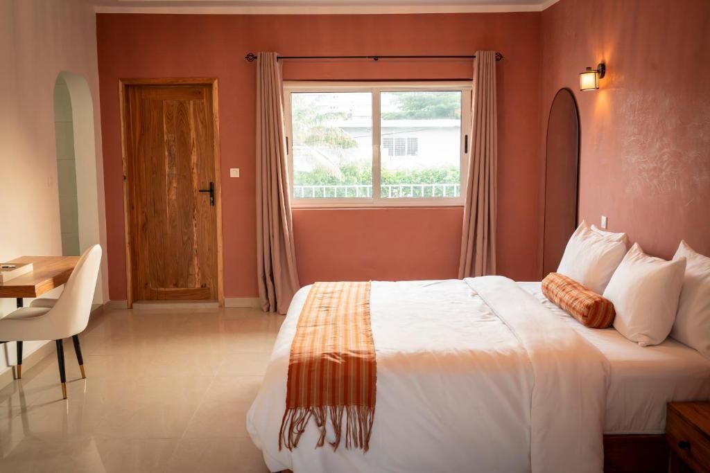 Ein Schlafzimmer mit Bett, Schreibtisch und einem fensterbepflanzten Fenster.