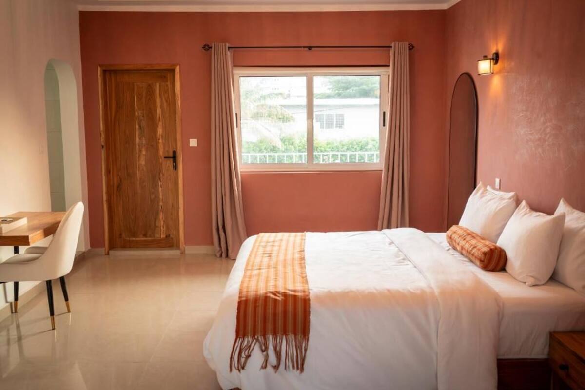 Un dormitorio con una cama, un escritorio y una ventana con cortinas.