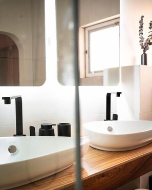 Ein Badezimmer mit einem weißen Waschbecken, einem schwarzen Wasserhahn und einer Holzplatte.