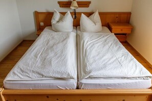 Un letto matrimoniale con testiera e pediera in legno, due comodini e una lampada fissata alla parete.