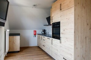 Eine kompakte Küche mit Holzschränken, einem eingebauten Backofen und einer Kaffeemaschine.