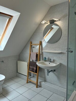 Ein Badezimmer mit Waschbecken, Spiegel, Handtuchhalter und Heizkörper.