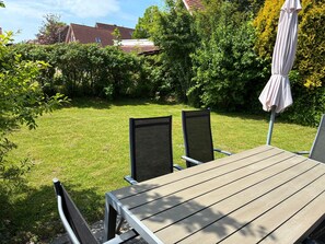 Ein Holztisch mit Stühlen in einem Garten mit Rasen und Bäumen.