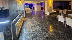 A hotel lobby with a reception desk, seating area, and a blue-lit corridor. - PAŞA MOTEL (Erdemli)