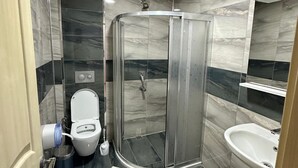 A modern bathroom with a glass-enclosed shower, a toilet, and a sink. - PAŞA MOTEL (Erdemli)