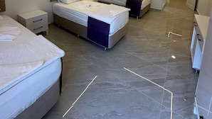 A modern hotel room with two beds, a nightstand, a wardrobe, and an air conditioning unit. - PAŞA MOTEL (Erdemli)