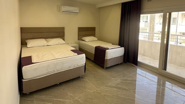 A modern hotel room with two beds, a large window, and a tiled floor. - PAŞA MOTEL (Erdemli)