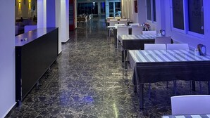 A hotel lobby with a reception desk, seating area, and a view into the dining area. - PAŞA MOTEL (Erdemli)