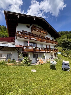 Ein mehrstöckiges Chalet mit Balkonen, einer Terrassenanlage und einem gepflegten Garten.