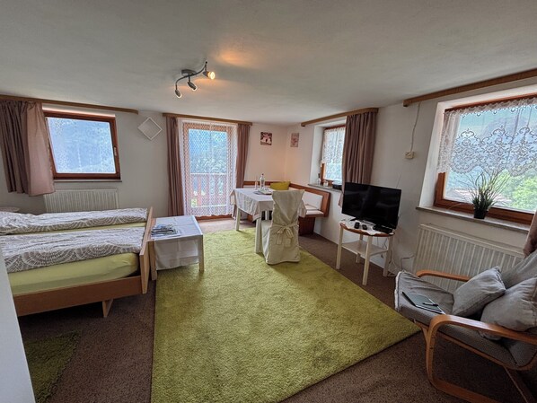 Ein Zimmer mit zwei Betten, einem Schreibtisch, einem Stuhl, einem Fernseher und großen Fenstern.