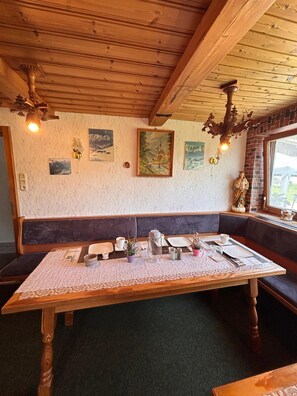 Ein Holzinterieur mit einem Esstisch, einer Bank und Wandbildern.