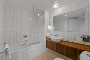 A modern bathroom with a glass-enclosed shower, a wooden vanity with a sink, and a large mirror. - Exclusive Stays - Gallery Towers (Southbank)