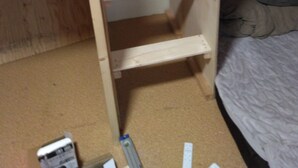 Una cama litera de madera con escalera, un estante individual y una pequeña zona de escritorio.