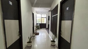 Un pasillo con puertas numeradas 101 y 102, plantas en macetas y una ventana al final.