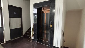 Un pasillo con una puerta negra marcada '101', una escalera y una barandilla.