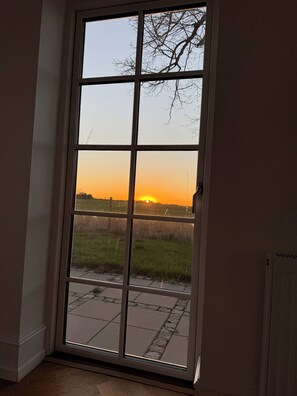 Uitzicht door een raam met een heldere lucht en een zonsondergang.