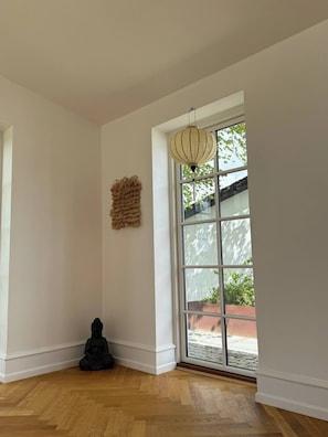 Ein Zimmer mit einem großen Fenster, einer Pendelleuchte und einer Buddha-Statue.
