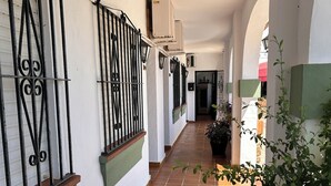 A corridor with tiled flooring, white walls, and black metal railings. - Hotel Apolo XI (Tarifa)