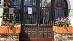 A reception area with a sign reading 'RECEPCION,' a wooden door with metal bars, and a tiled entrance. - Hotel Apolo XI (Tarifa)