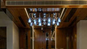 A reception desk with a marble top, wooden paneling on the walls, and a modern chandelier with multiple spherical lights. - Regenta Place The Golden Castle Baddi (Baddi)