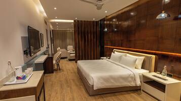 Una habitación de hotel con cama, mesita de noche, escritorio, silla y espejo.