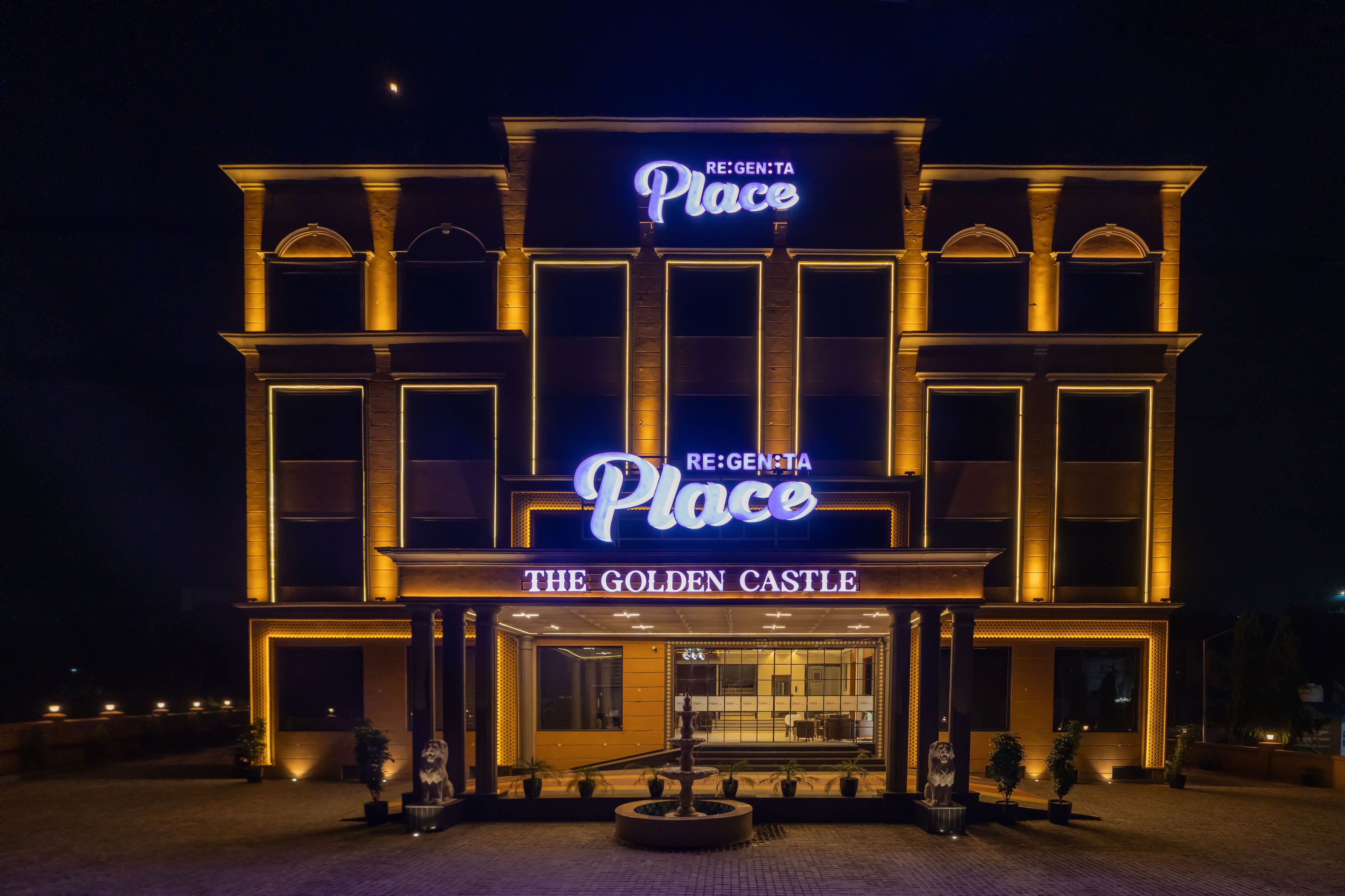 Entrada de un hotel con un cartel luminoso que dice 'RE:GEN:TA Place THE GOLDEN CASTLE'.