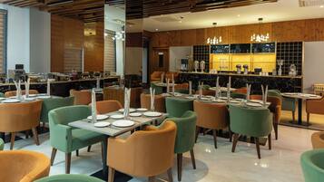 A modern restaurant with multiple tables and chairs, a bar area, and a wooden ceiling.