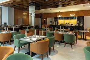 A modern restaurant with multiple tables and chairs, a bar area, and a wooden ceiling. - Regenta Place The Golden Castle Baddi (Baddi)