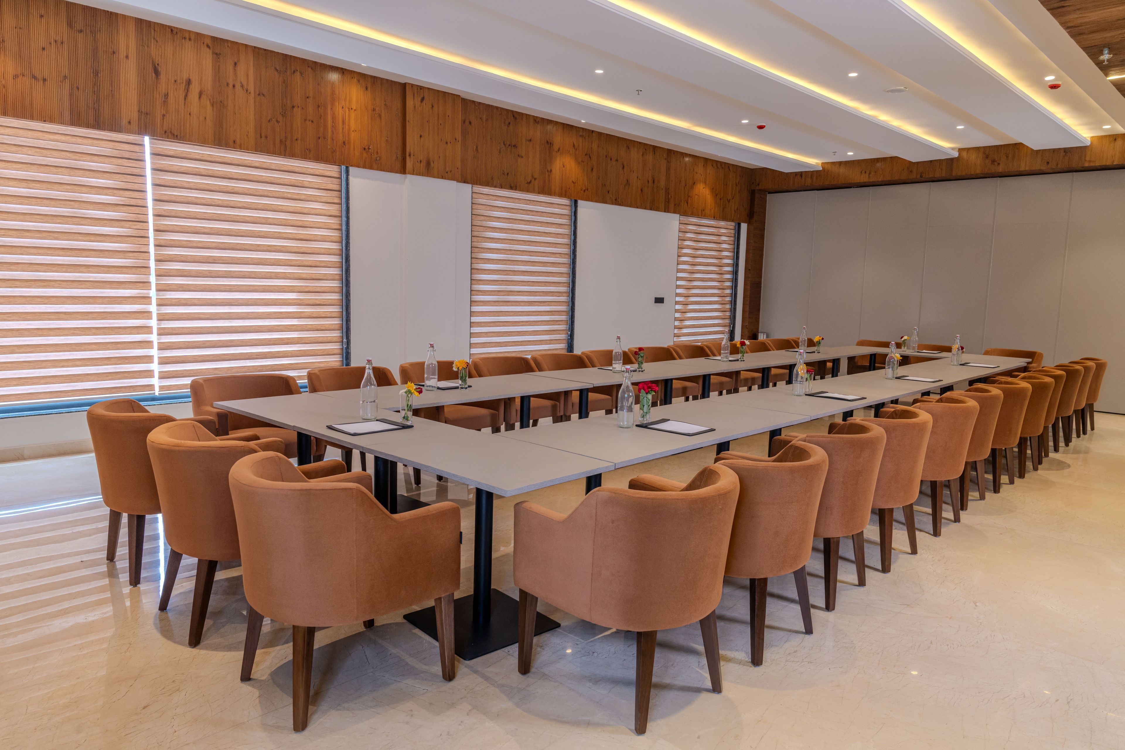 A conference room with a long table, multiple chairs, and a projector screen.