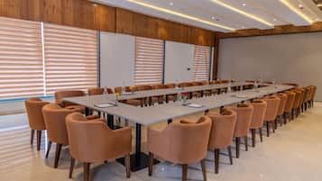 A conference room with a long table, multiple chairs, and a projector screen.