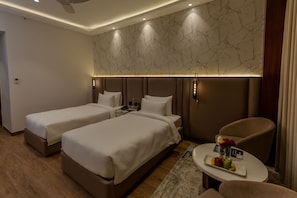 Een hotelkamer met twee bedden, een zithoekje met een tafeltje en een wand met marmerlook.