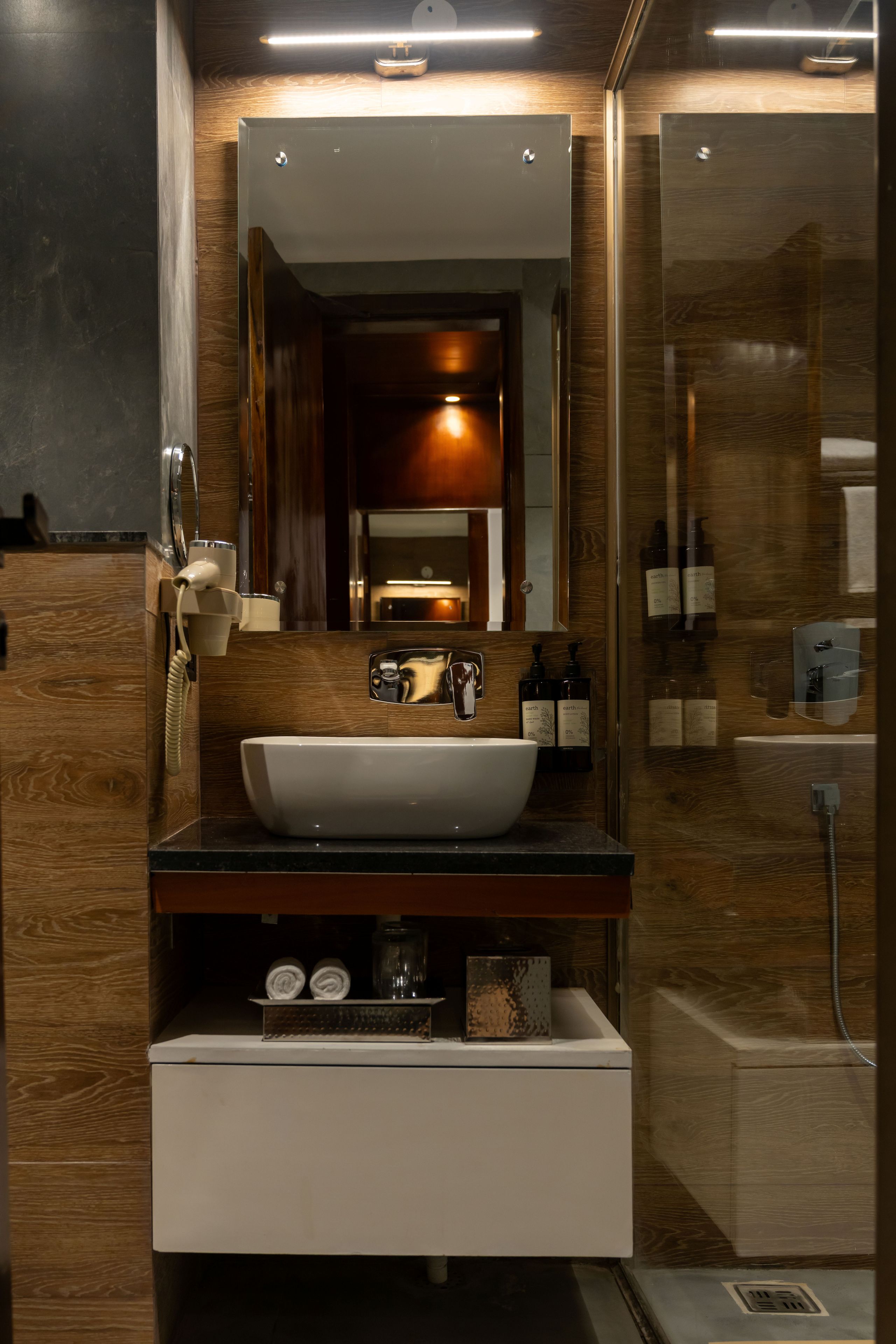 A modern bathroom with a large mirror, a white sink, and a glass shower enclosure.