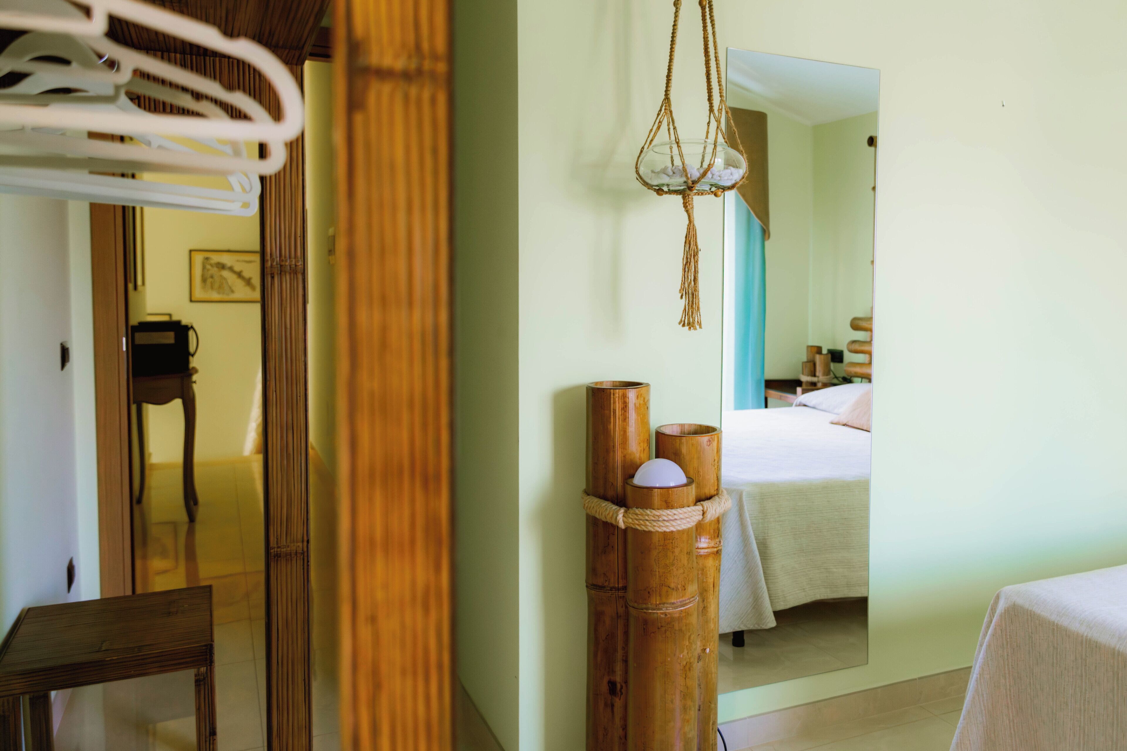 Ein Hotelzimmer mit Bett, Spiegel, Holzschemel und einer h ängenden Makramee-Dekoration.