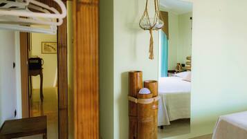 Ein Hotelzimmer mit Bett, Spiegel, Holzschemel und einer hängenden Makramee-Dekoration.