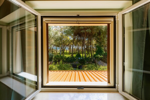 An open window with a view of a garden and a wooden deck.